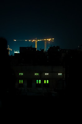Evening view of a construction site lit up with green and gold pumps working as the city skyline glows.
