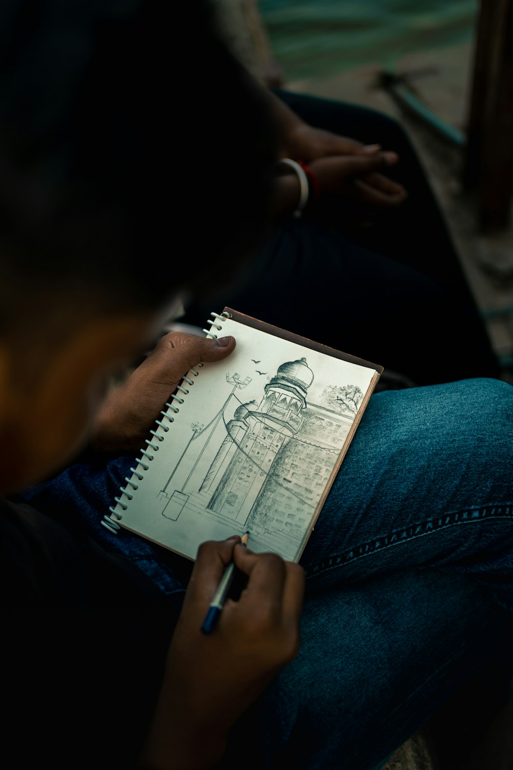 a person sitting down writing on a notebook