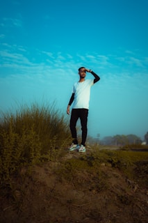 A confident individual standing atop a hill, looking out over a vast landscape.