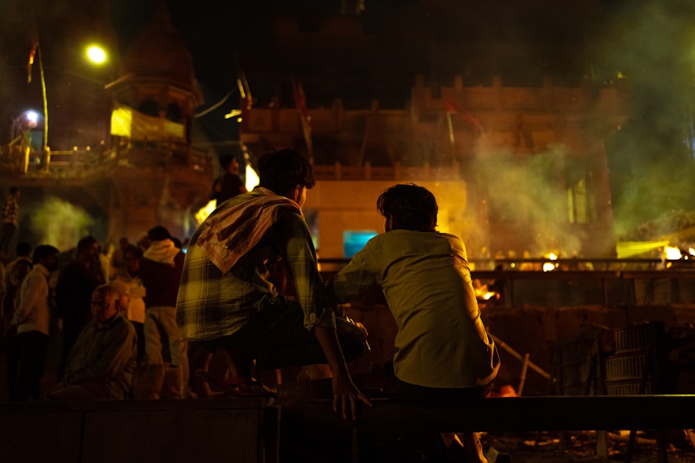 two people sitting on a bench in front of a crowd of people