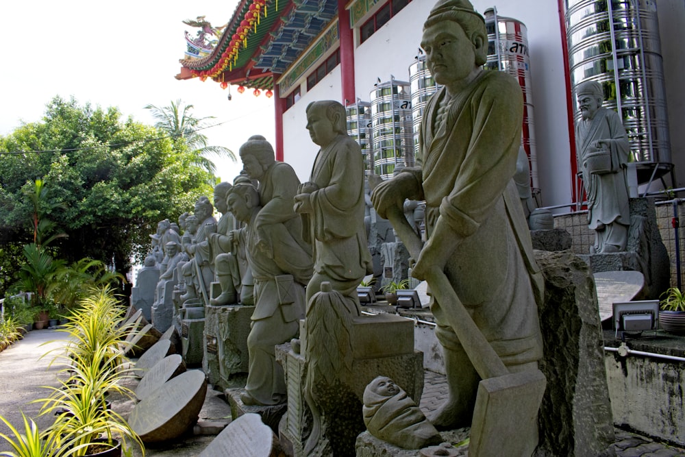 Una hilera de estatuas de hombres sosteniendo palas frente a un edificio