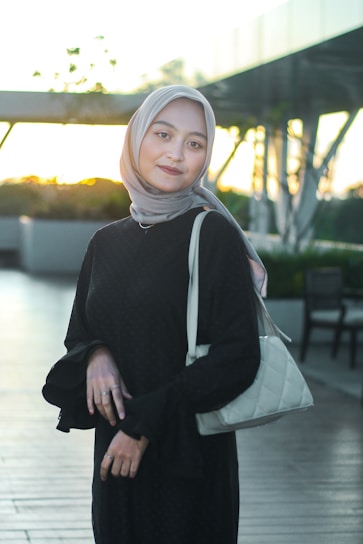 a woman wearing a hijab and carrying a purse