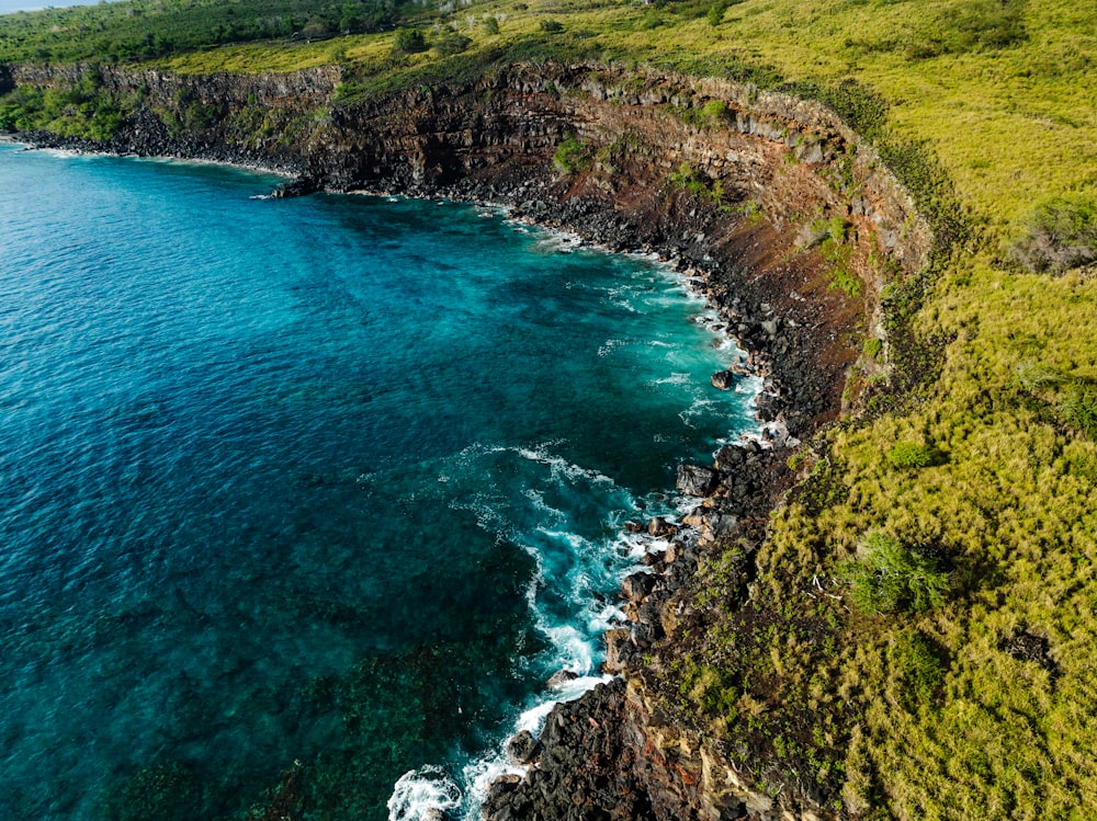 a large body of water next to a lush green hillside