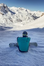 a person sitting in the snow with a snowboard