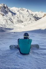 a person sitting in the snow with a snowboard