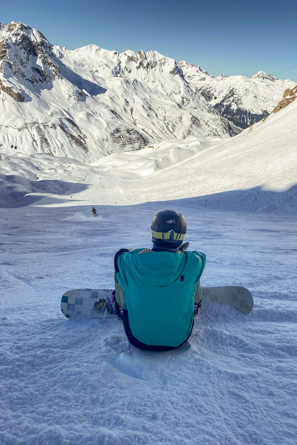 a person sitting in the snow with a snowboard