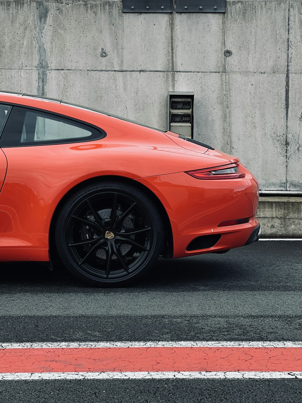 a bright orange sports car parked on the side of the road