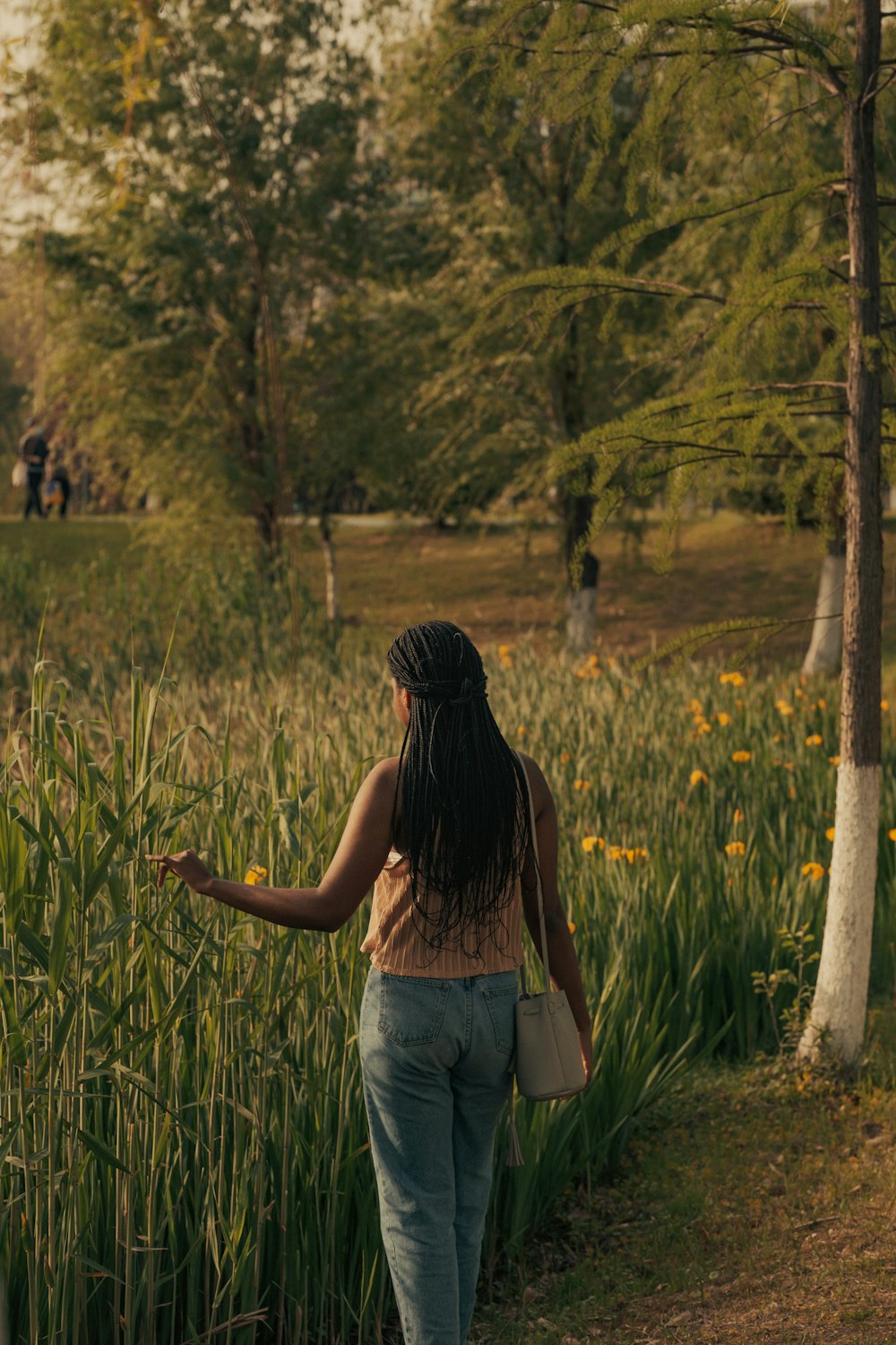 a woman walking through a field of tall grass