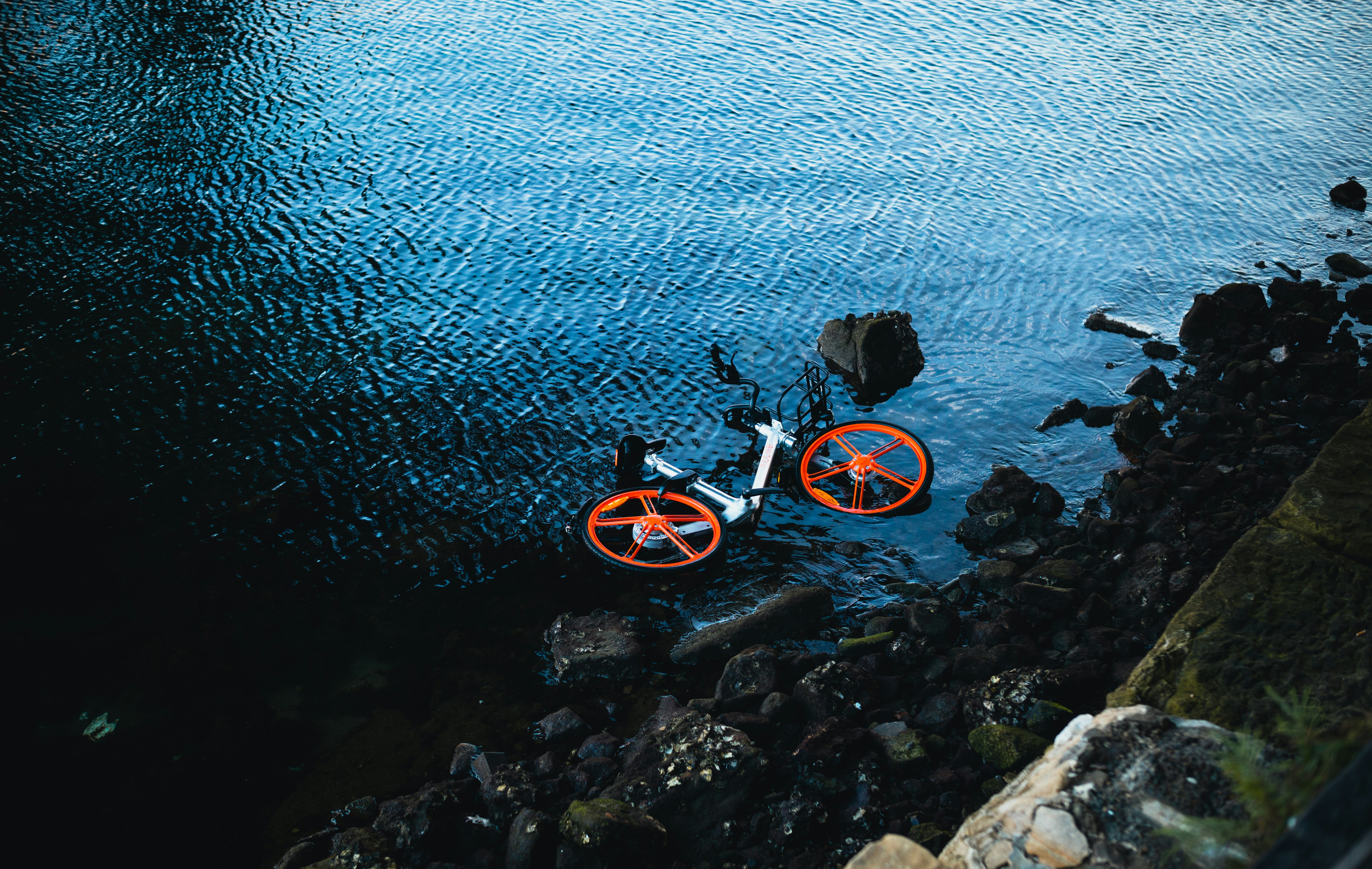 an orange bike sitting in the middle of a body of water