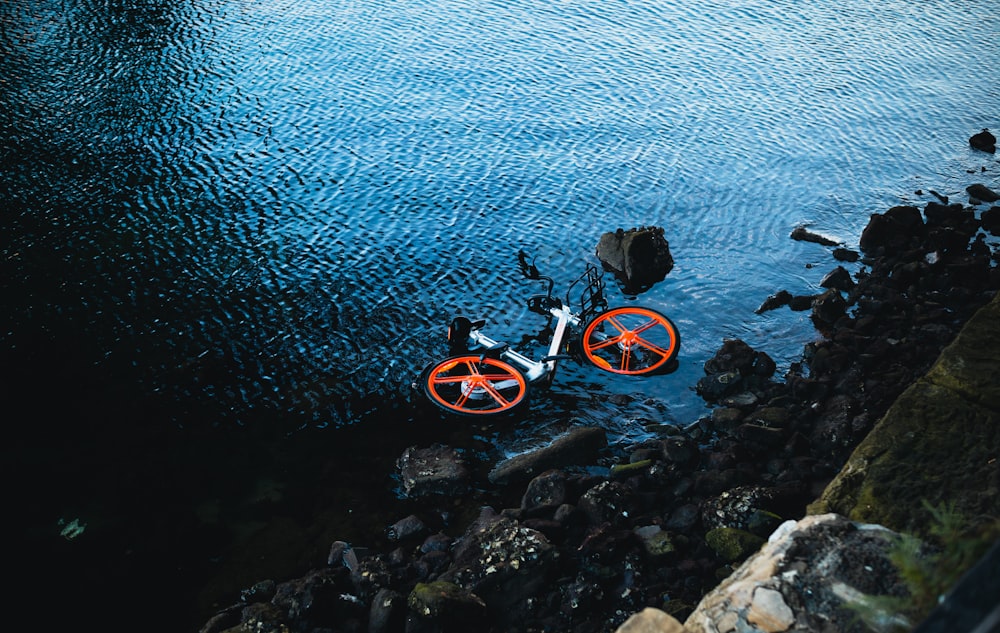 an orange bike sitting in the middle of a body of water