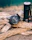 Image of a rugged emergency radio and flashlight set resting on a wooden picnic table with forest background.