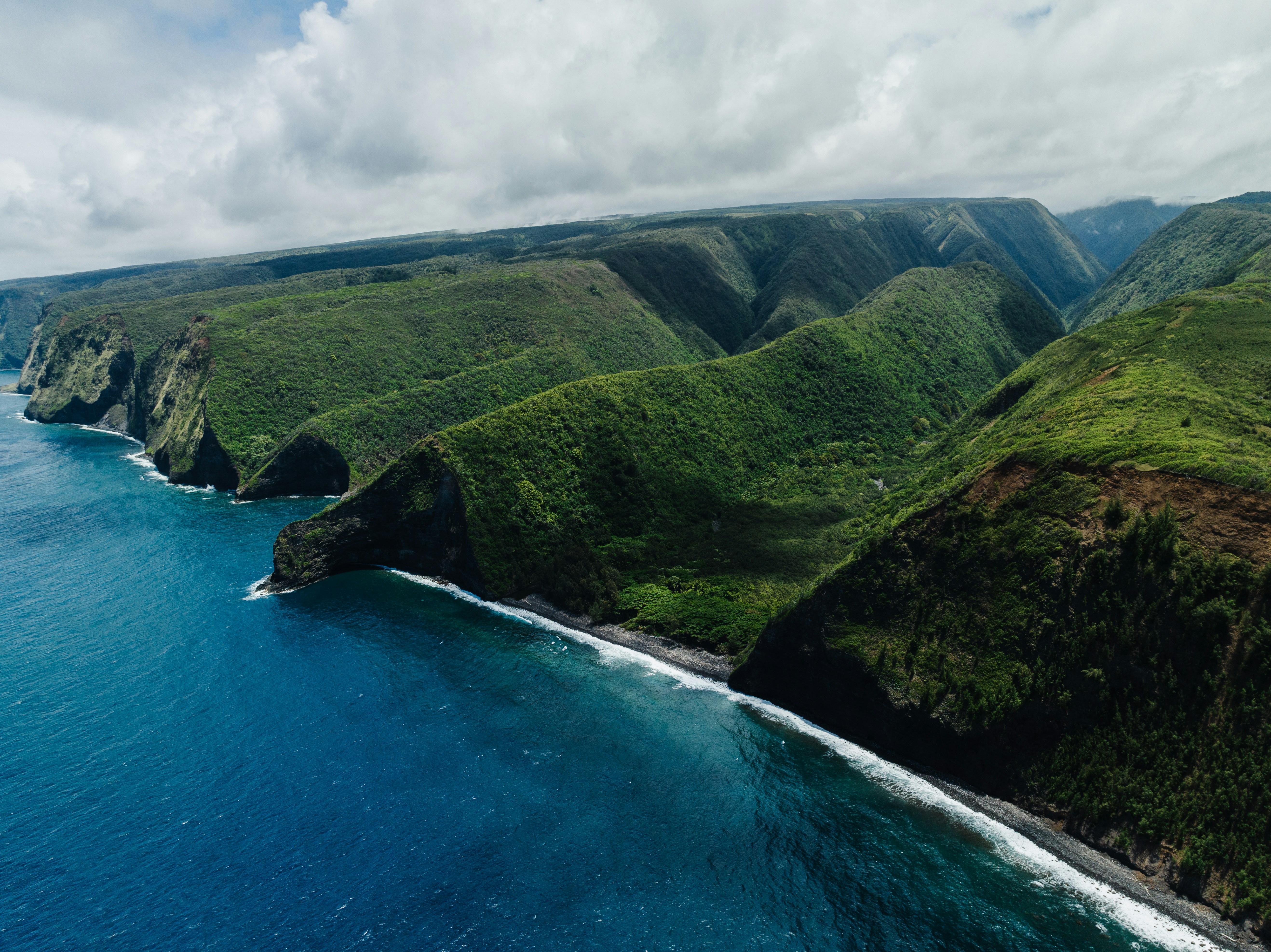 an aerial view of a lush green hillside next to the ocean