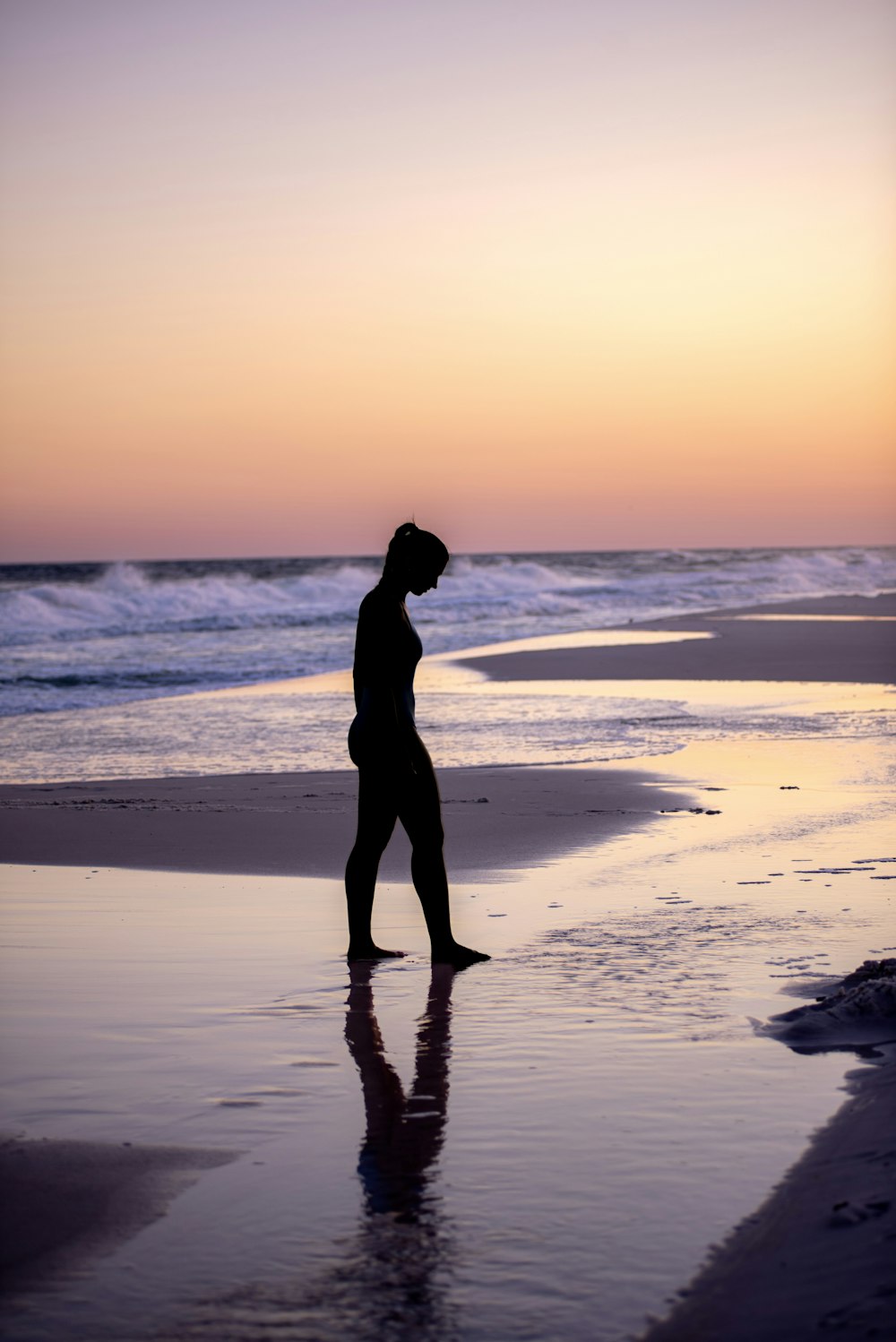 a person walking on the beach at sunset