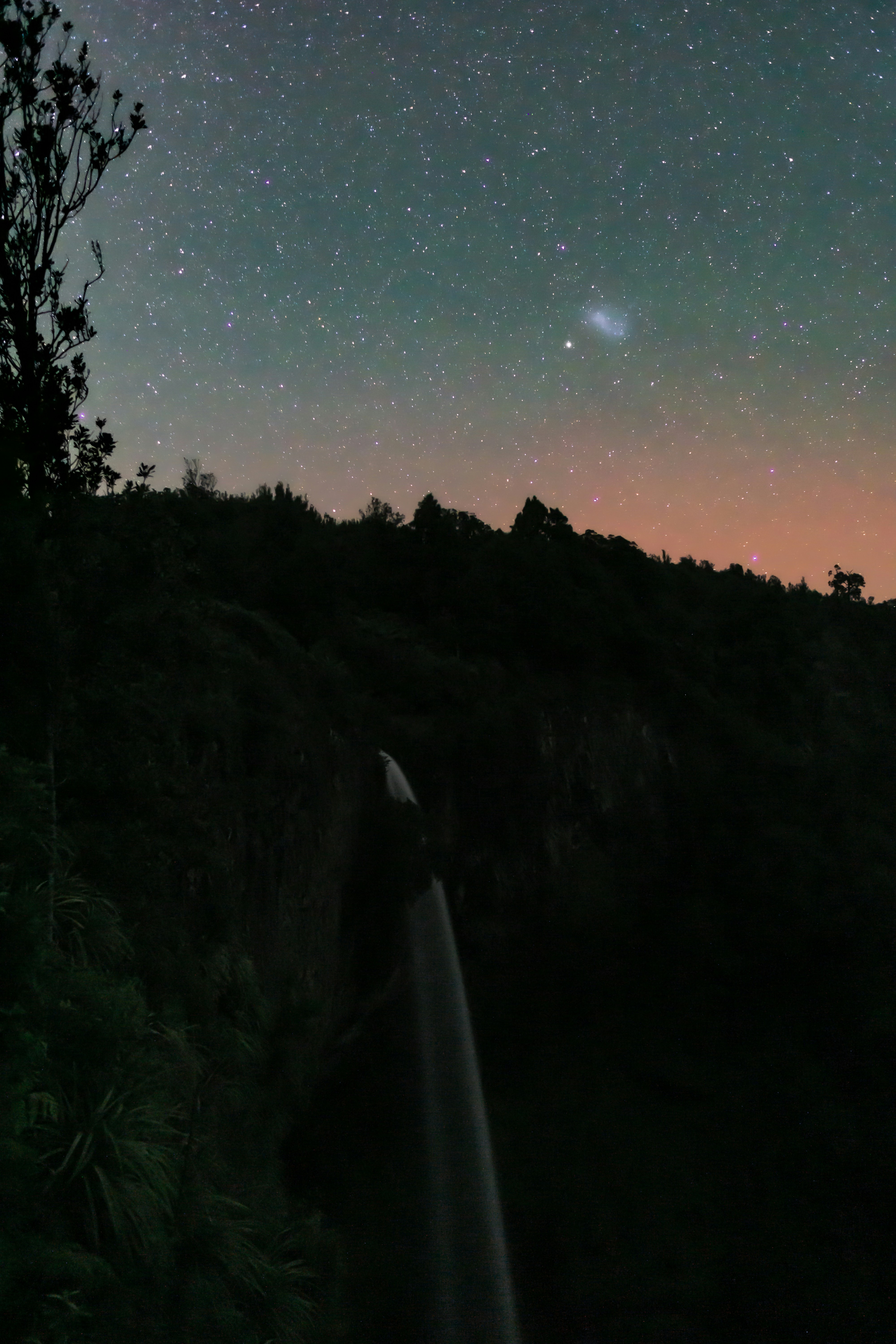 the night sky with stars above a mountain