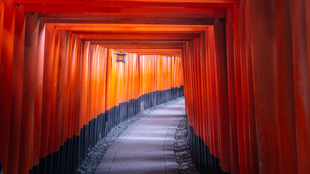 a walkway lined with red columns leading to a light