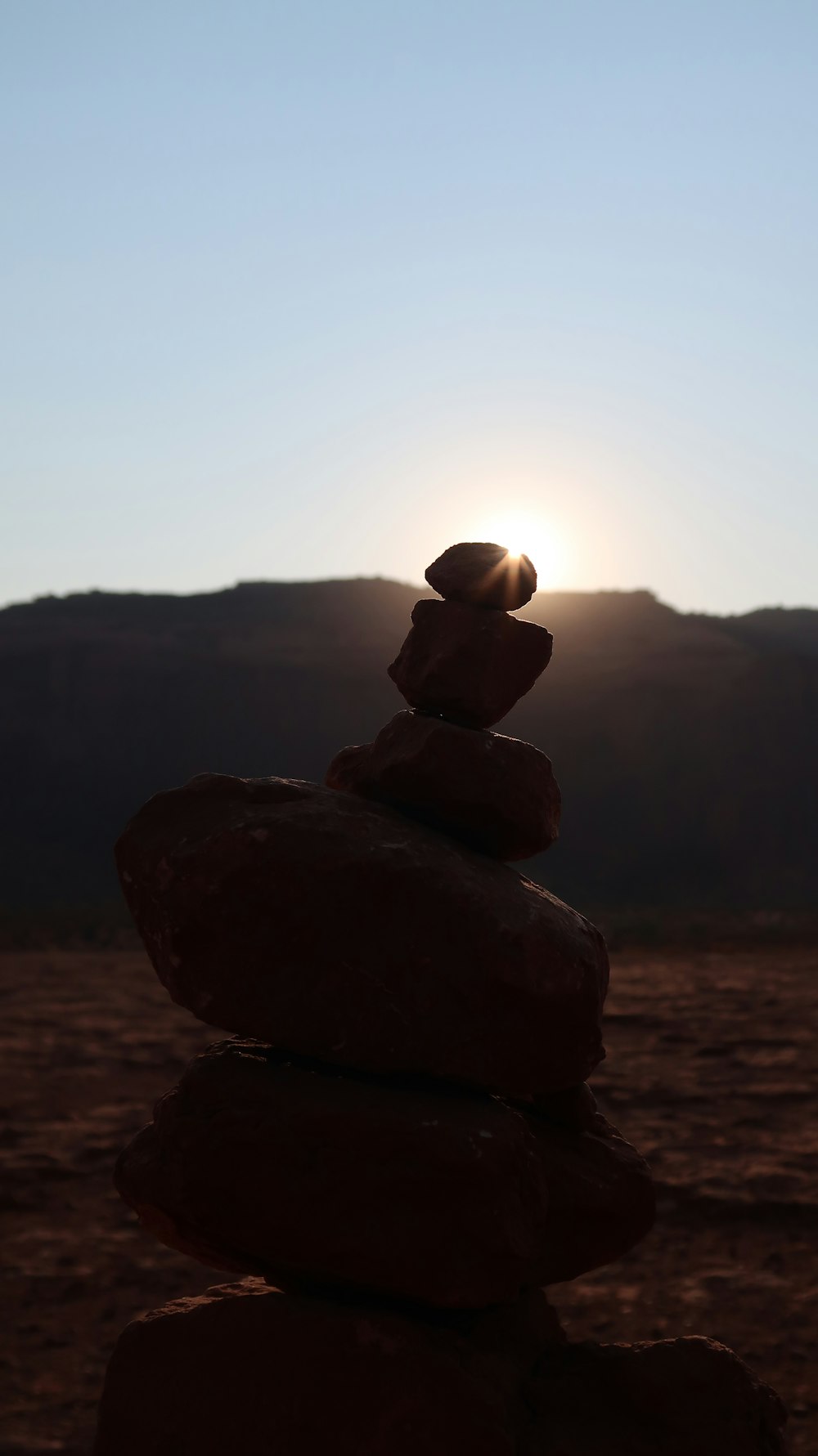 a stack of rocks with the sun setting in the background