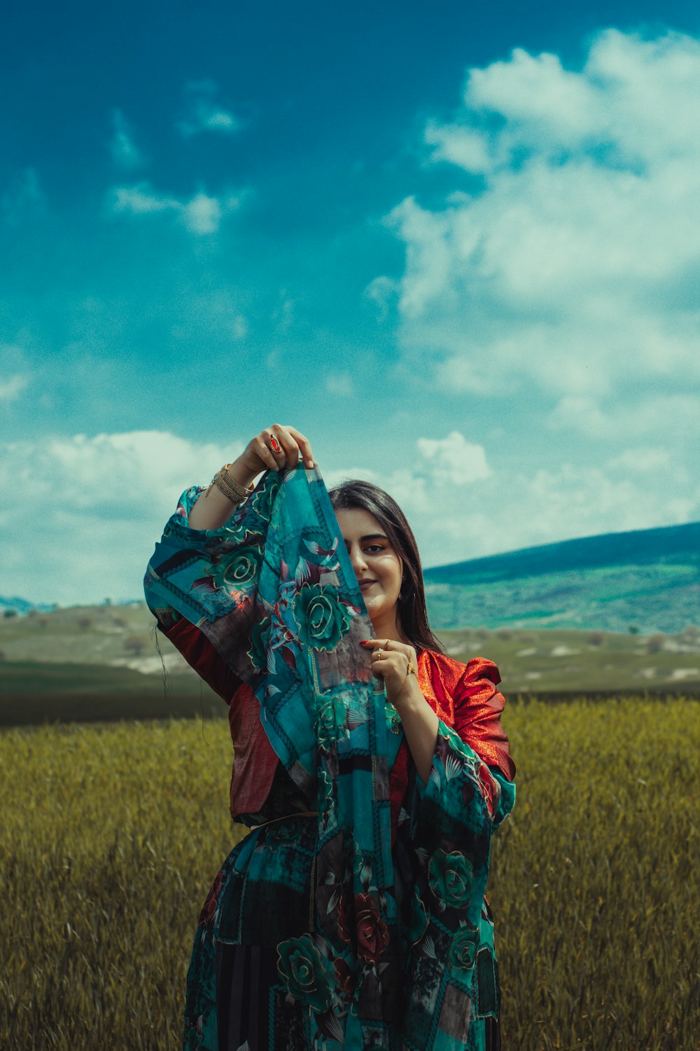 a woman standing in a field holding a scarf