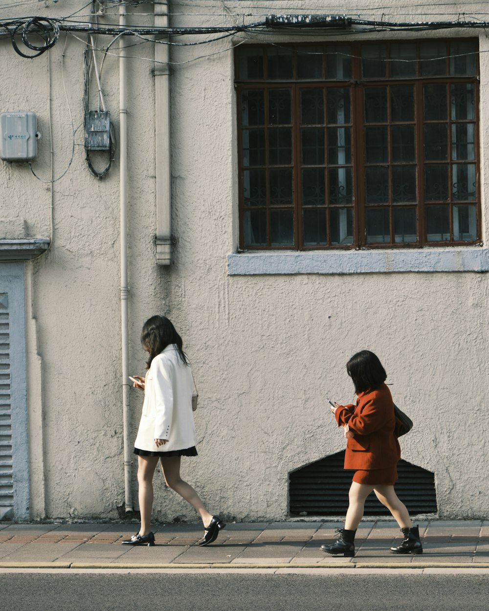 a couple of women walking down a street next to a building