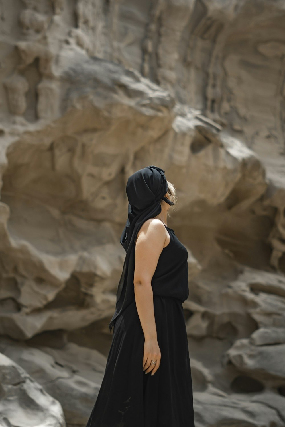Eine Frau in einem schwarzen Kleid steht vor einer Felsformation