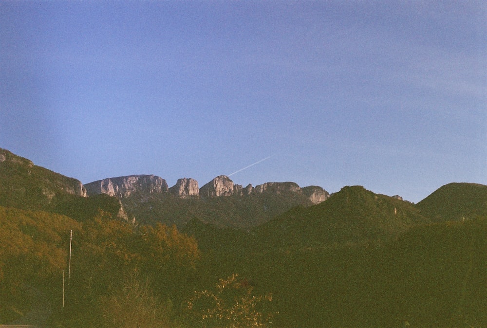 a view of a mountain range with a plane flying in the sky