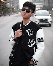 A sleek black-and-white photo of a young person confidently wearing a Streetmart jacket on a city street.