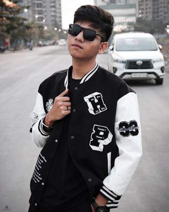 A sleek black-and-white photo of a young person confidently wearing a Streetmart jacket on a city street.