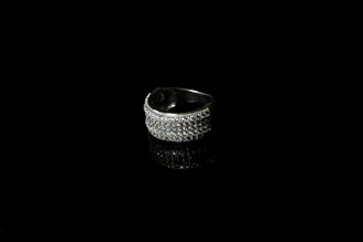 Close-up of a sleek, contemporary silver ring resting on a textured black surface, highlighting its clean lines and craftsmanship.