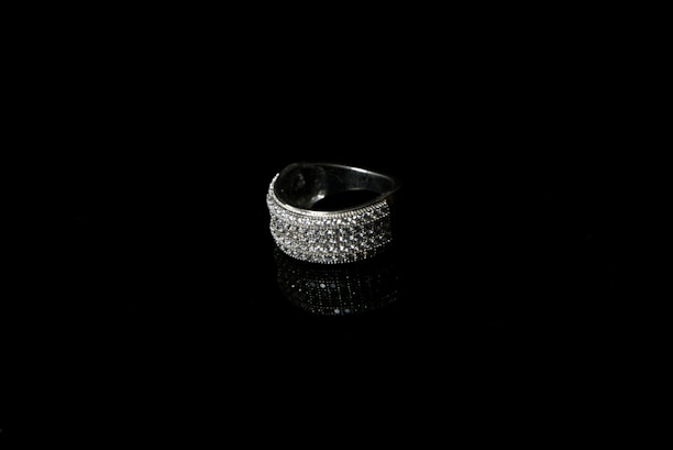 Close-up of a luxury graduation ring on a deep black background with subtle golden highlights.