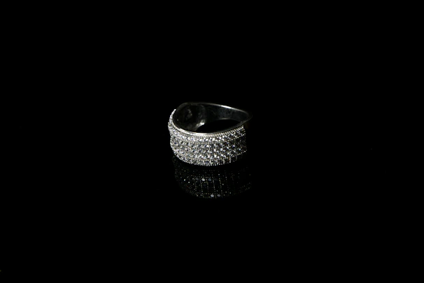 Close-up of a sleek, contemporary silver ring resting on a textured black surface, highlighting its clean lines and craftsmanship.