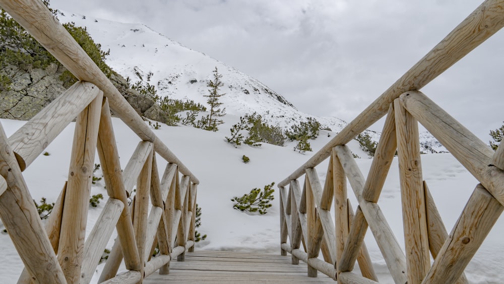 a wooden bridge with snow on the ground