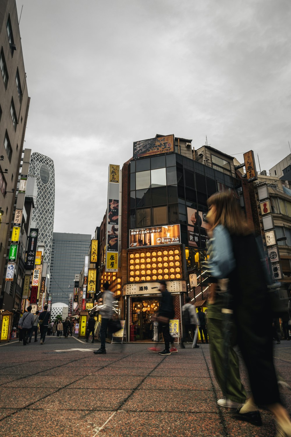 a group of people walking down a street next to tall buildings