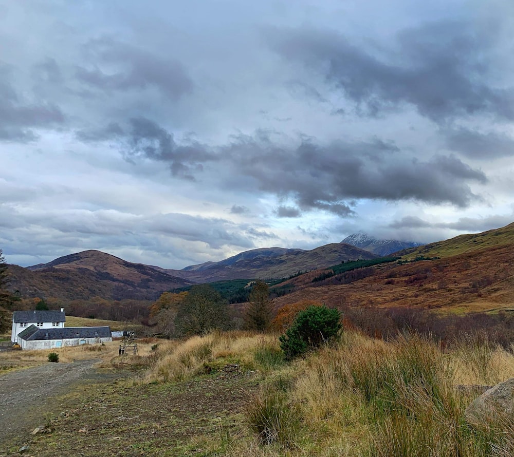 a house in the middle of a field with mountains in the background