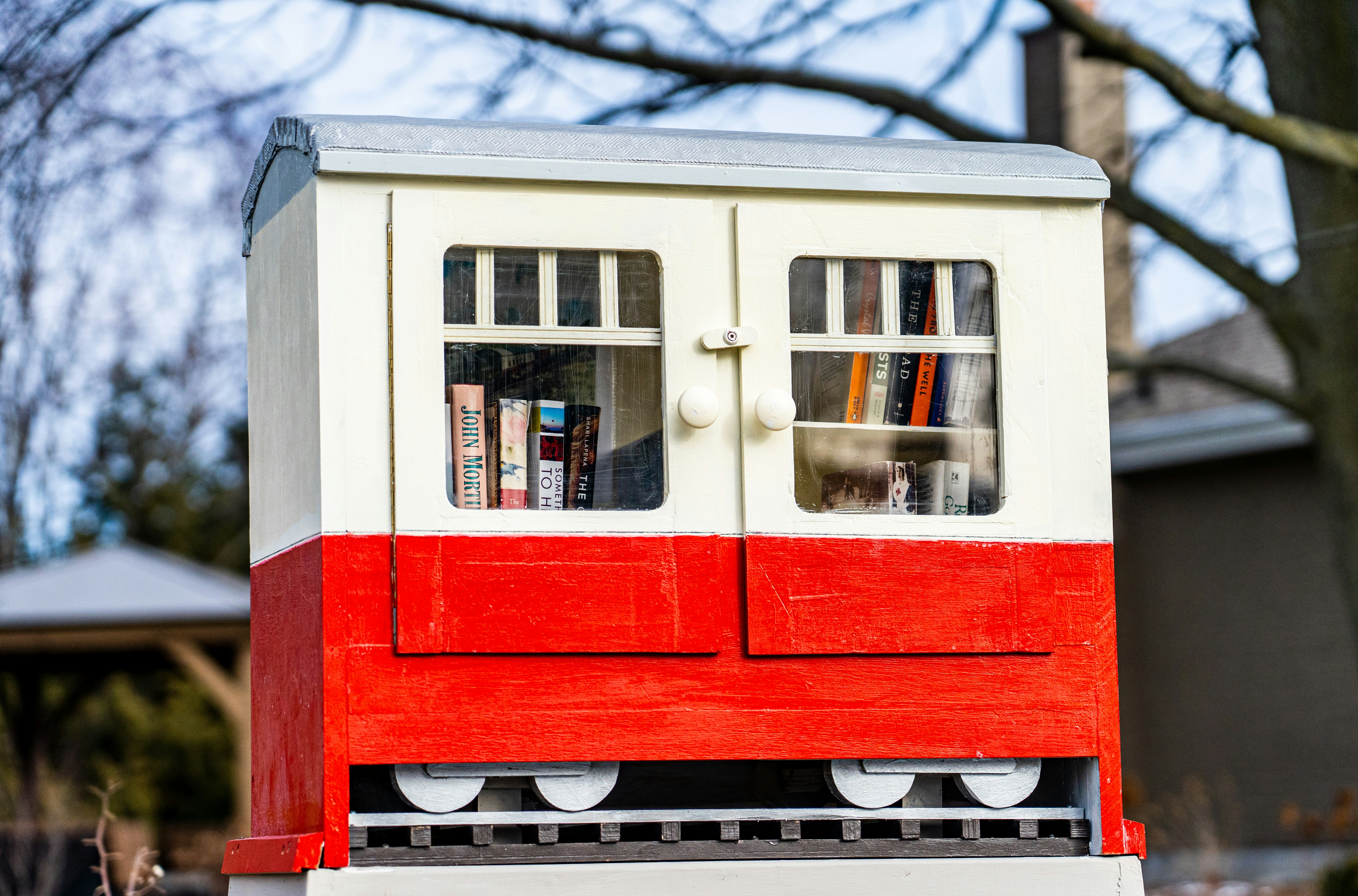 A wooden Little Free Library box painted red and white