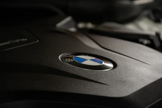 Close-up of a shiny BMW engine cover displayed in a modern showroom.