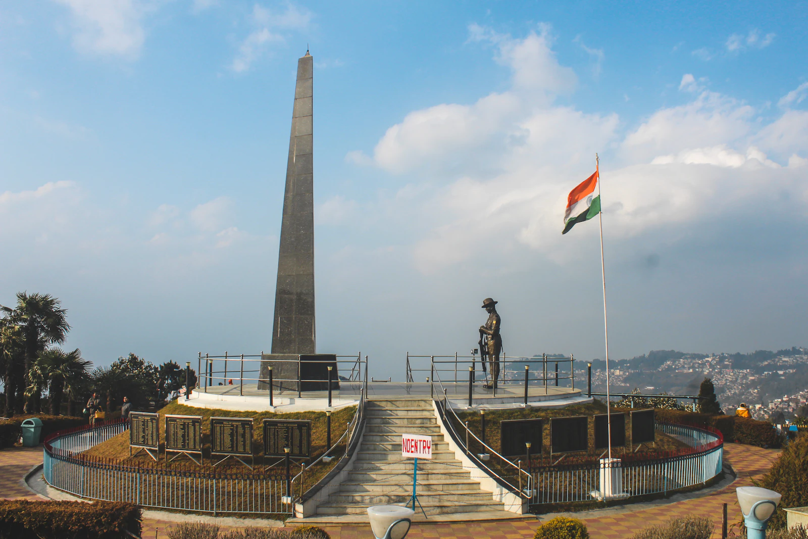 The Gorkha war memorial and the national flag in the terraced garden of the Batasia Loop, Darjeeling, under a blue sky