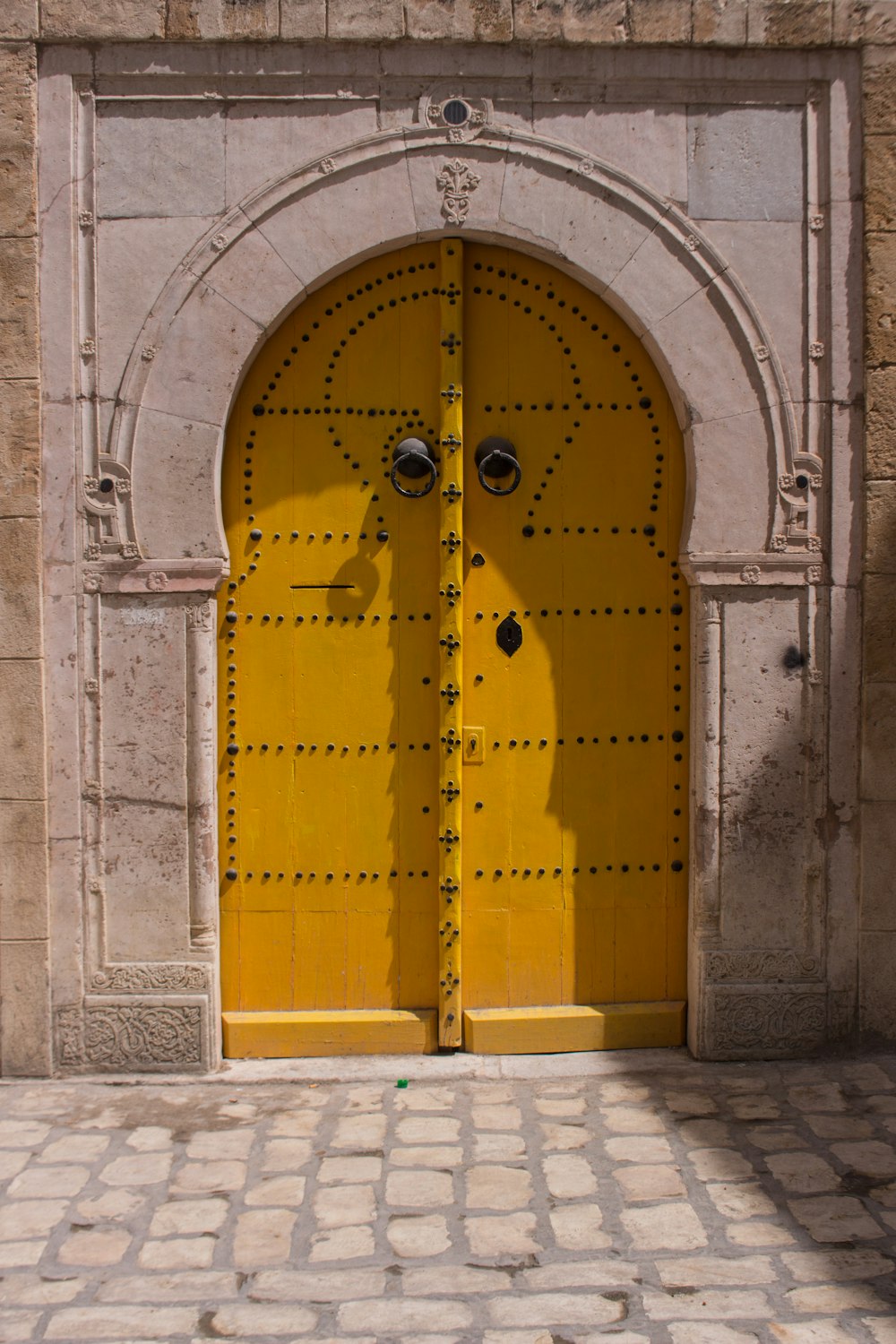 a large yellow door with a brick walkway in front of it