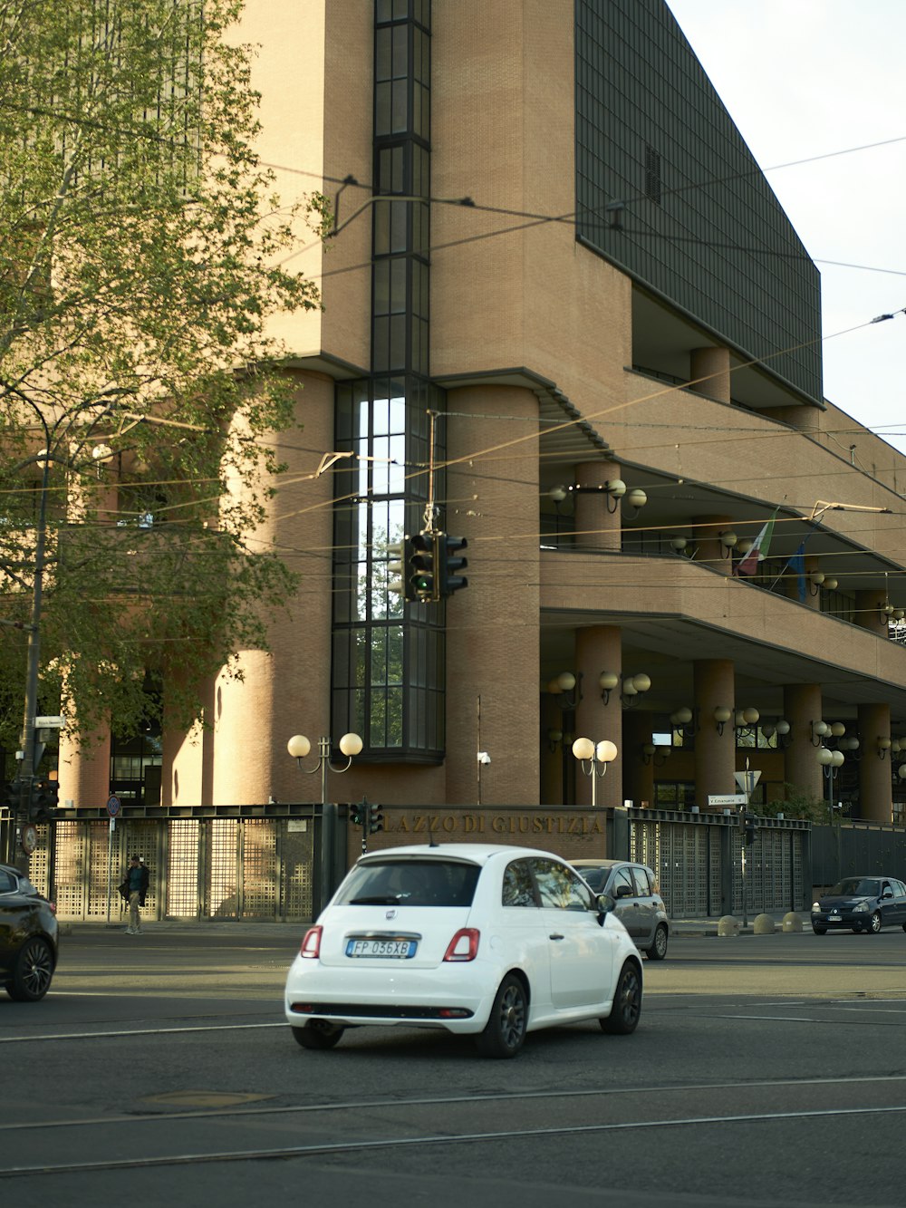 a white car driving down a street next to a tall building