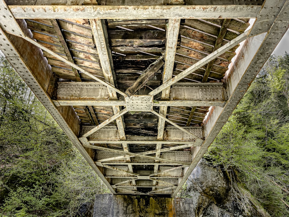 the underside of a wooden bridge over a river