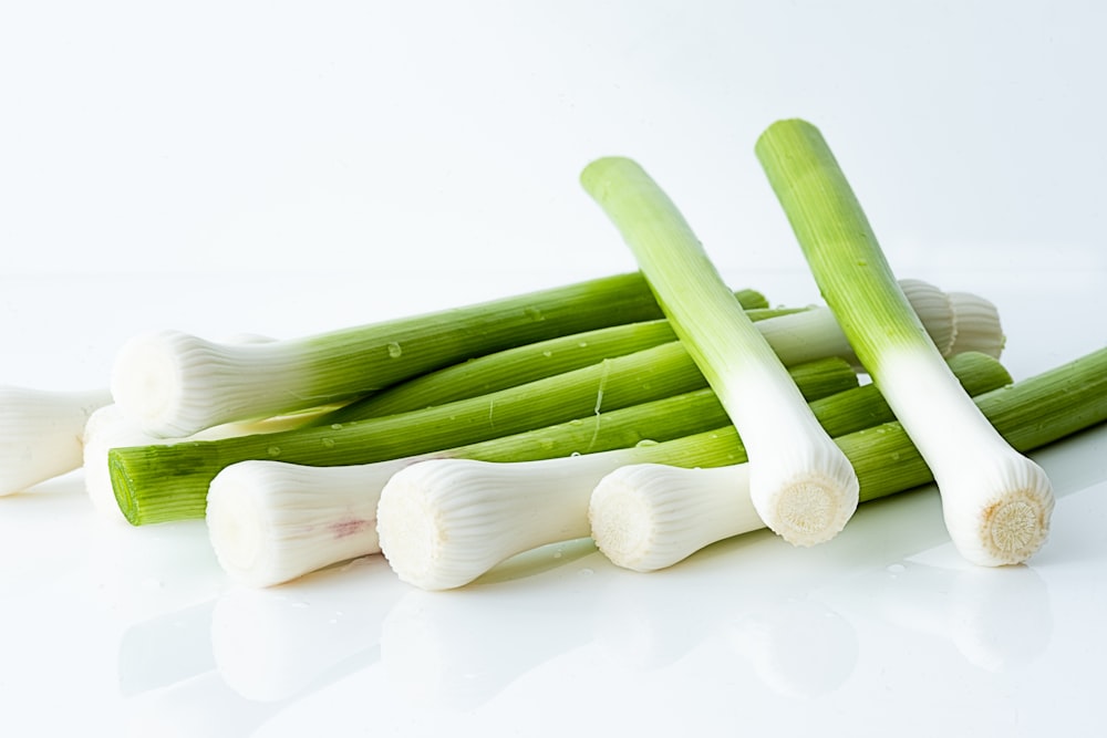 a pile of celery and onions on a white surface