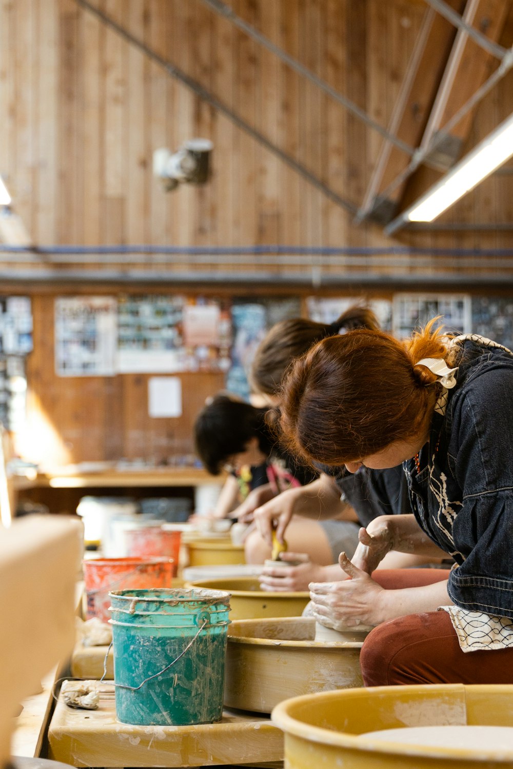 a group of women sitting at a table working on pottery