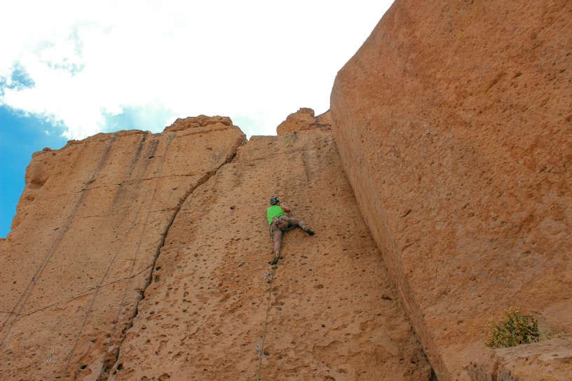 a man climbing up the side of a large rock