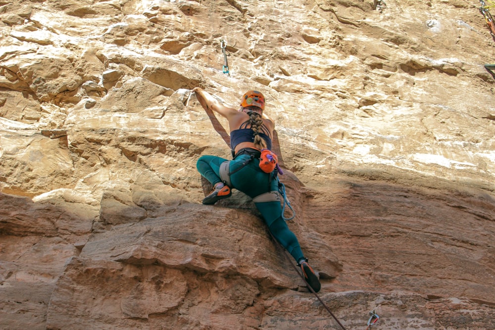a woman climbing up a mountain with a rope