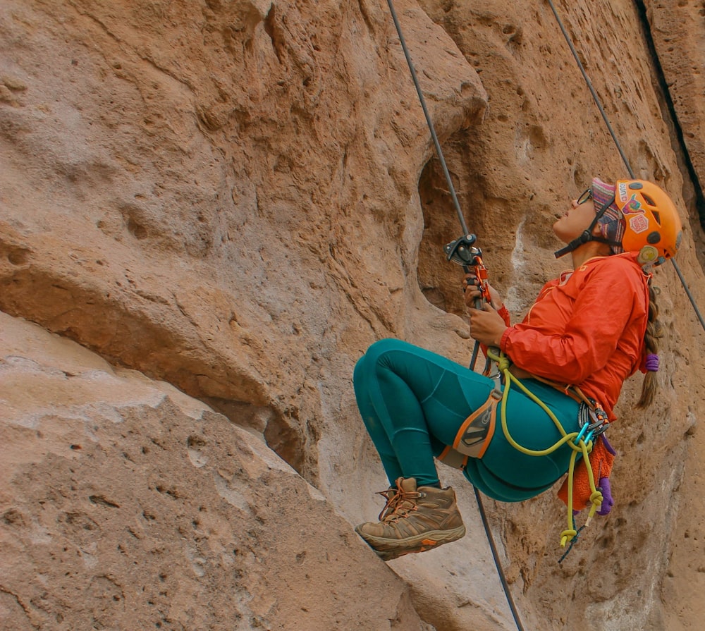 a woman climbing up the side of a mountain