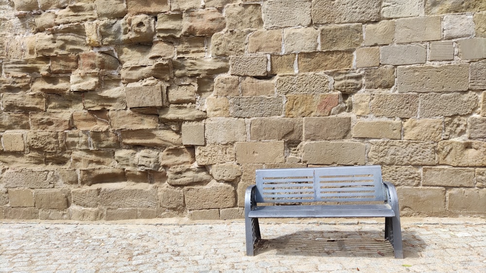 a bench sitting in front of a stone wall