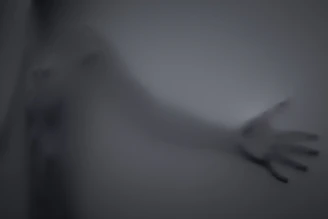 A mysterious digital ghostly figure emerging from a glowing computer screen in a dark room.