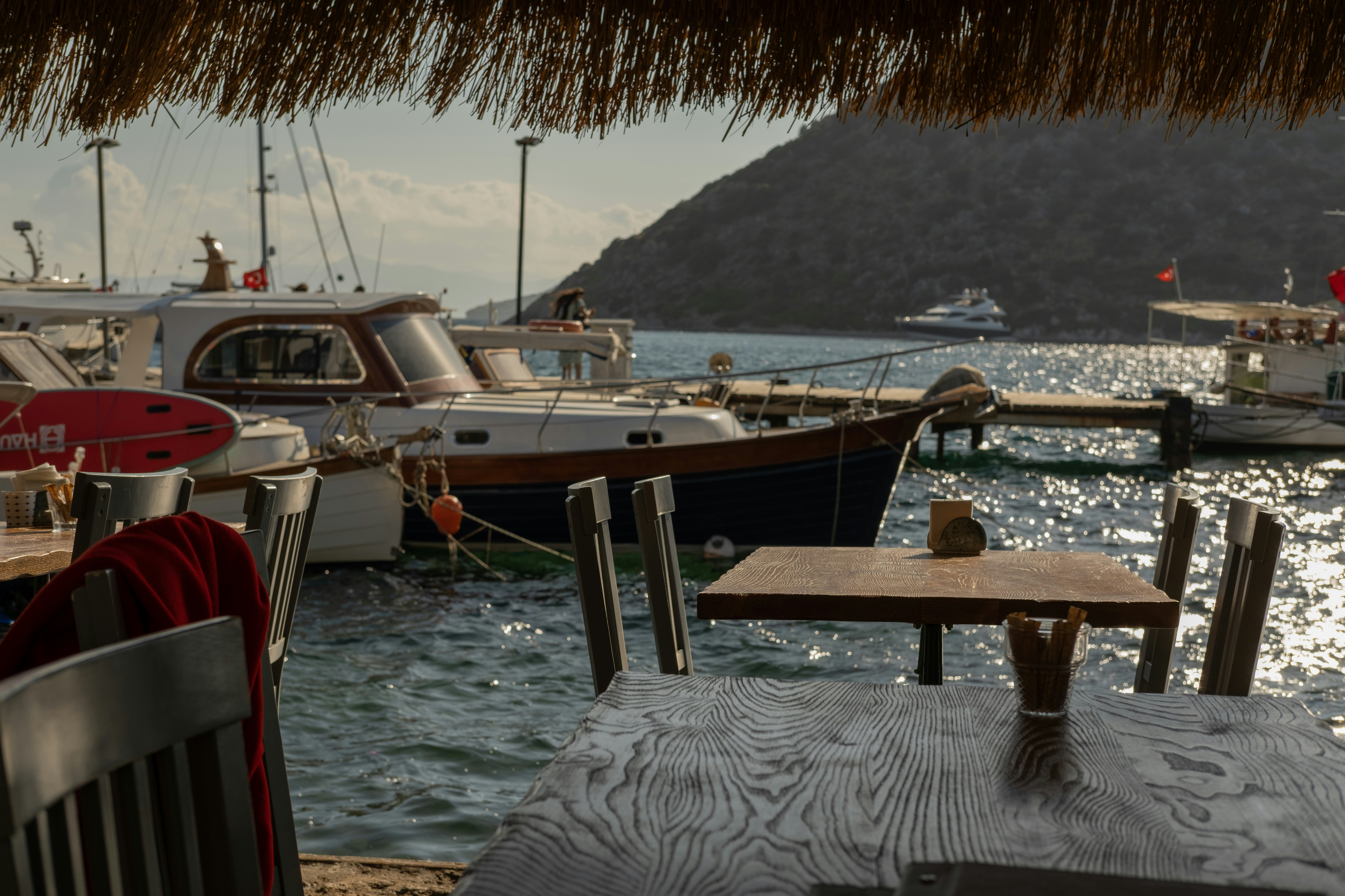 Table and chairs on a waterfront dock next to moored boats near the Harbor café