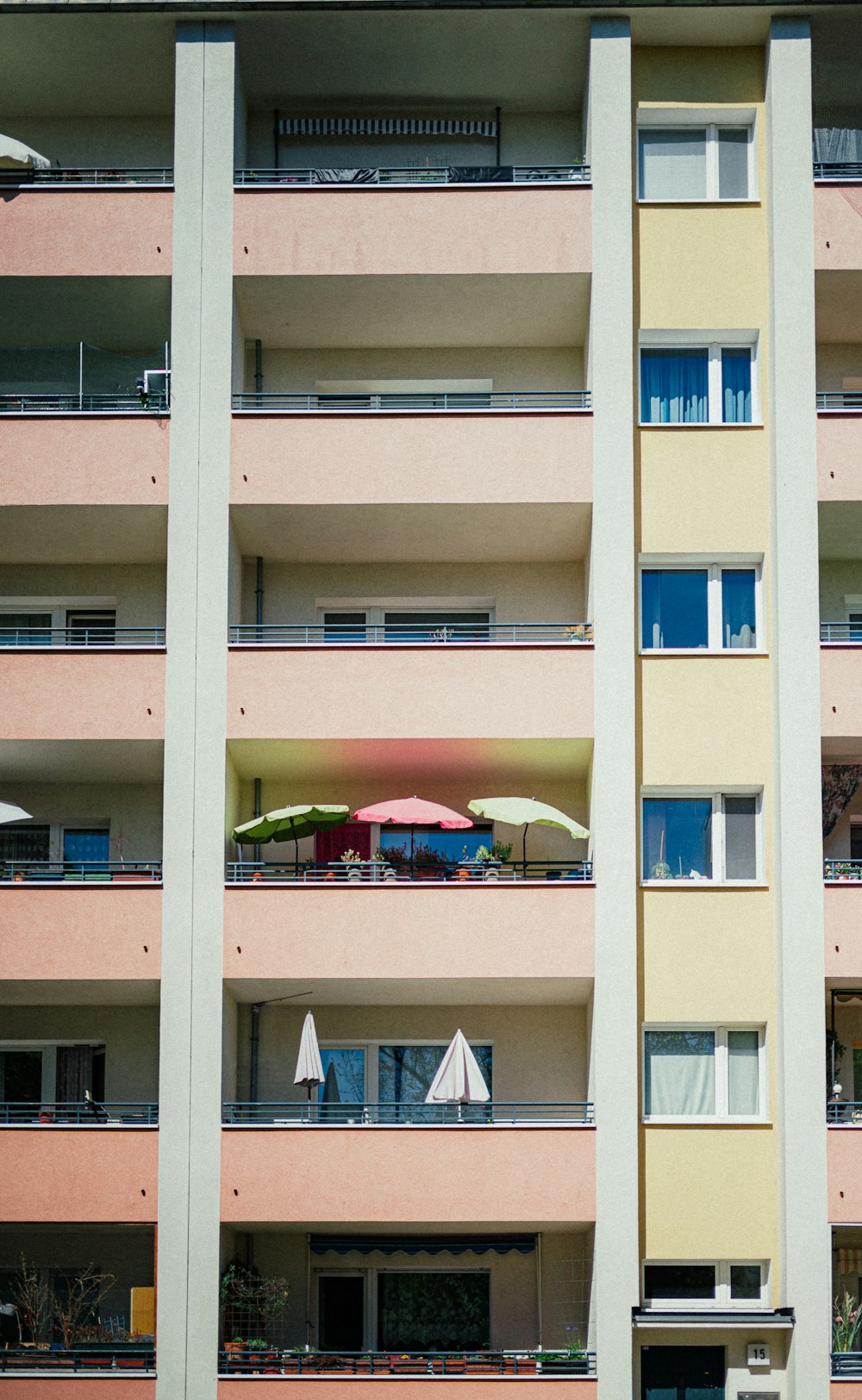 ein Mehrfamilienhaus mit Balkonen und Sonnenschirmen auf den Balkonen