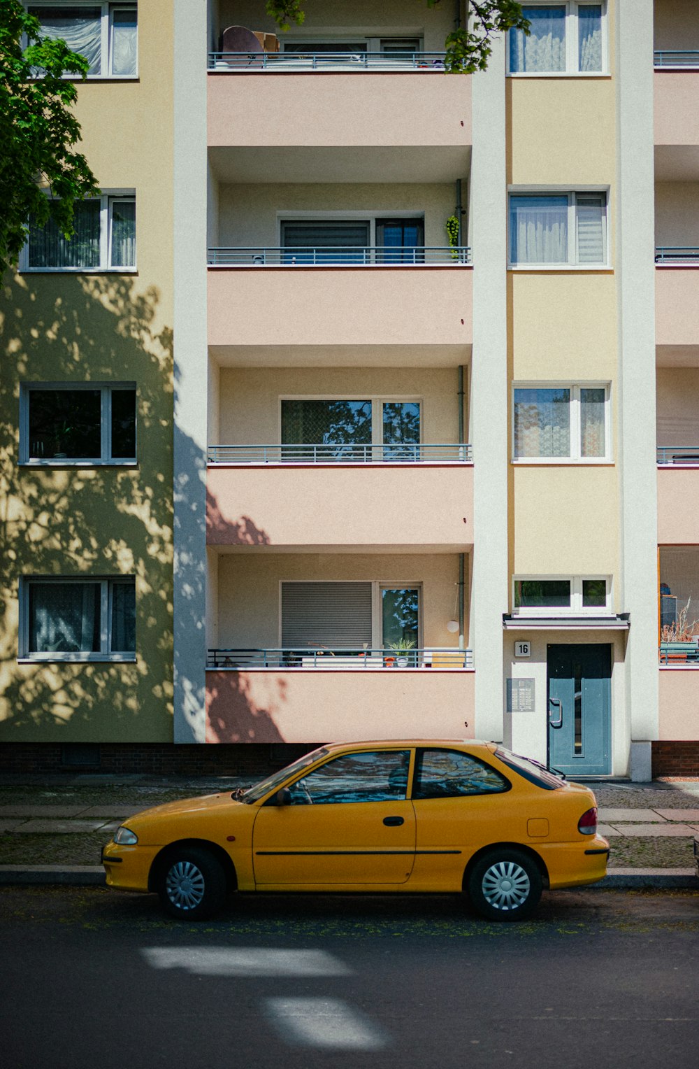 um carro amarelo estacionado em frente a um prédio alto