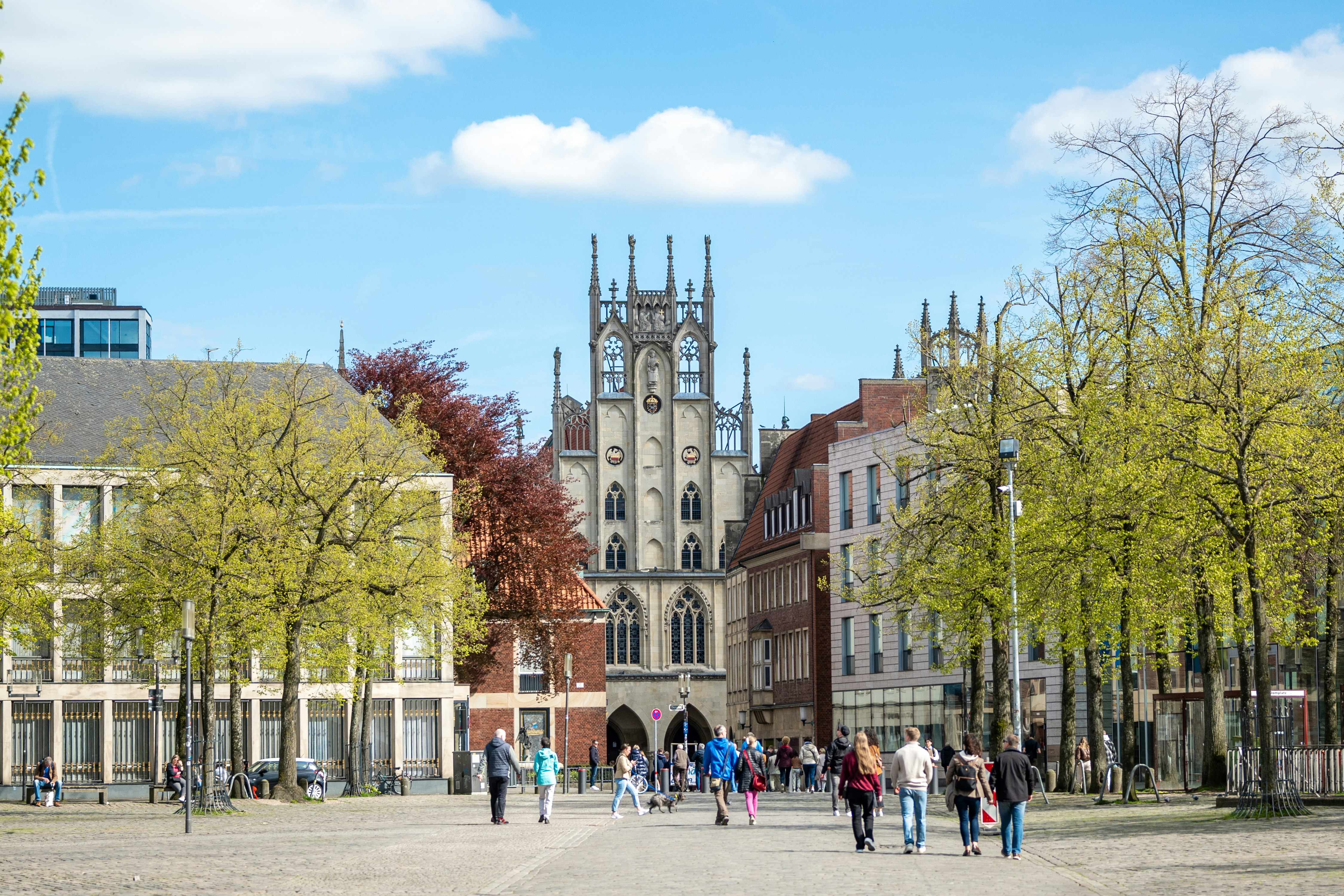 a group of people walking down a street next to tall buildings