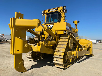 Close-up of a bulldozer blade pushing earth with a dark blue and gold color theme